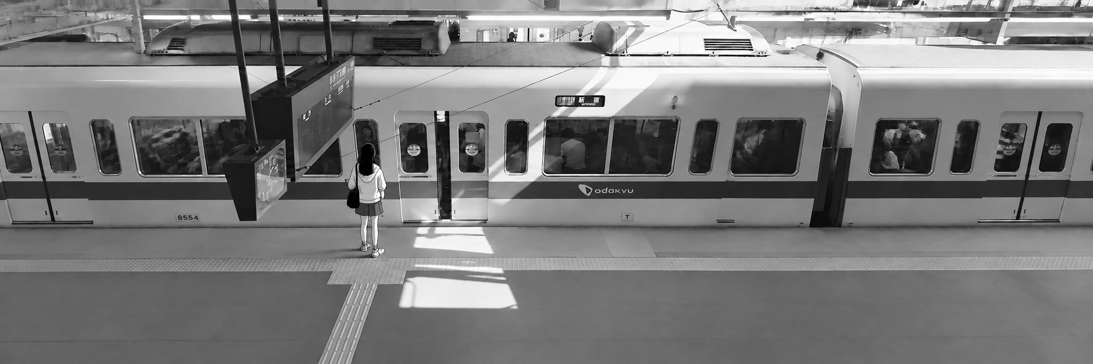 Persona observando un tren desde una plataforma iluminada.